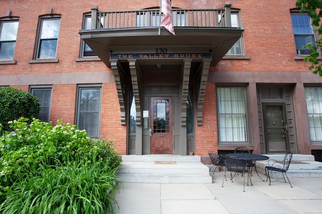 property entrance featuring brick siding and a balcony