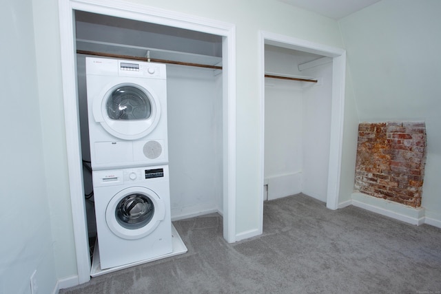 laundry area featuring laundry area, stacked washer / dryer, carpet flooring, and baseboards