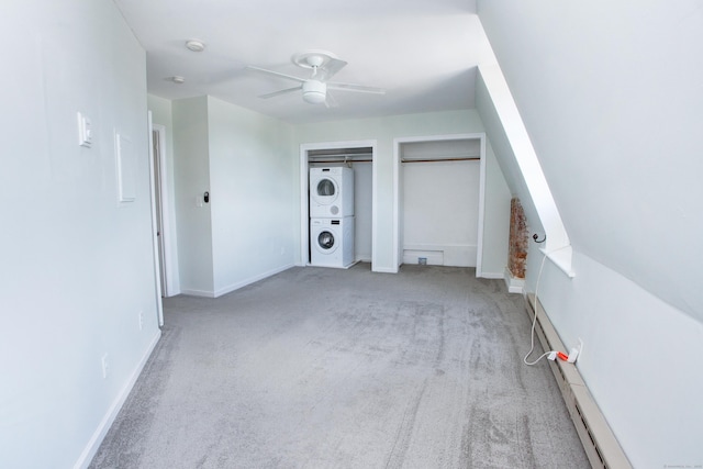 interior space featuring baseboards, stacked washing maching and dryer, a ceiling fan, and light colored carpet