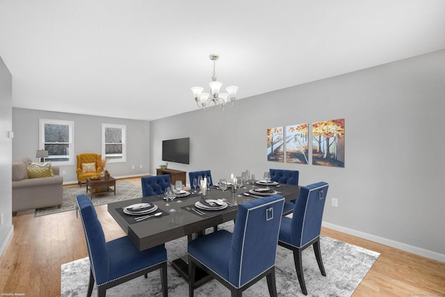 dining space with baseboards, wood finished floors, and a notable chandelier