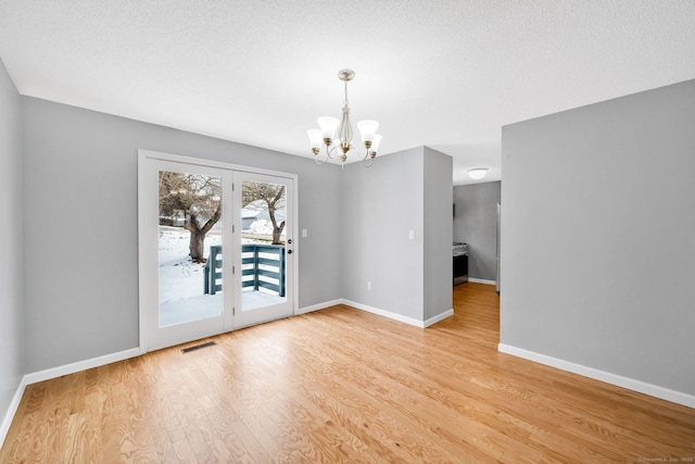 unfurnished dining area featuring a chandelier, visible vents, light wood-style flooring, and baseboards