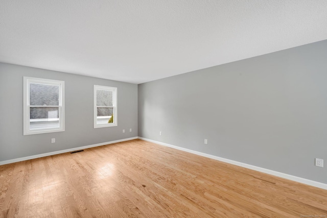 spare room with visible vents, light wood-style flooring, and baseboards