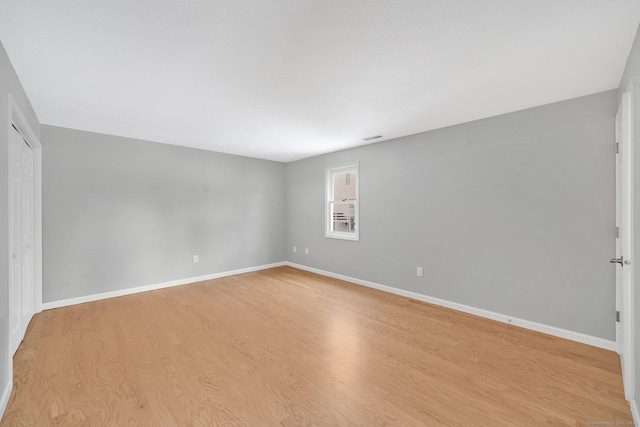 spare room featuring baseboards and light wood finished floors