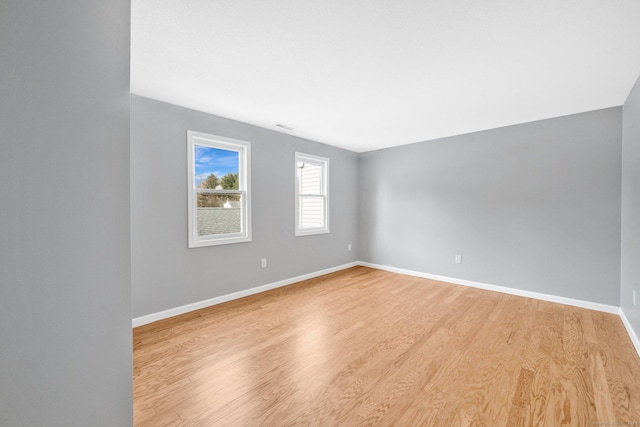 spare room featuring baseboards and light wood finished floors