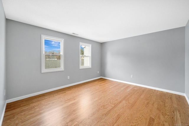 spare room with visible vents, light wood-style flooring, and baseboards