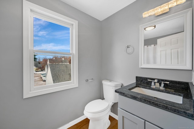 full bathroom featuring wood finished floors, vanity, toilet, and baseboards