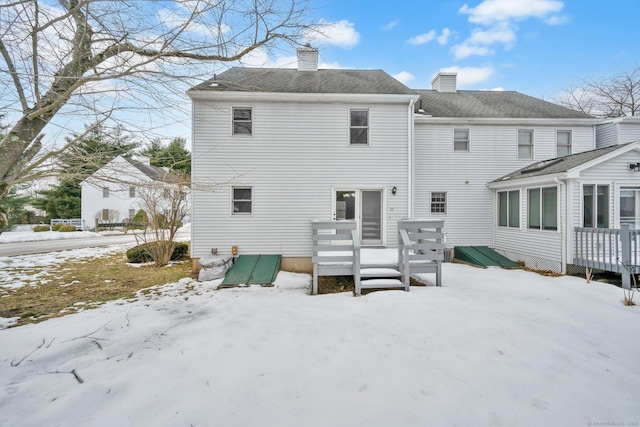 snow covered property featuring a chimney and a wooden deck