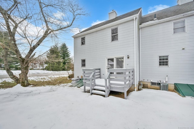 snow covered property featuring a chimney and a wooden deck