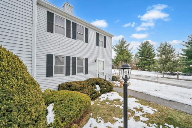 snow covered property with a chimney