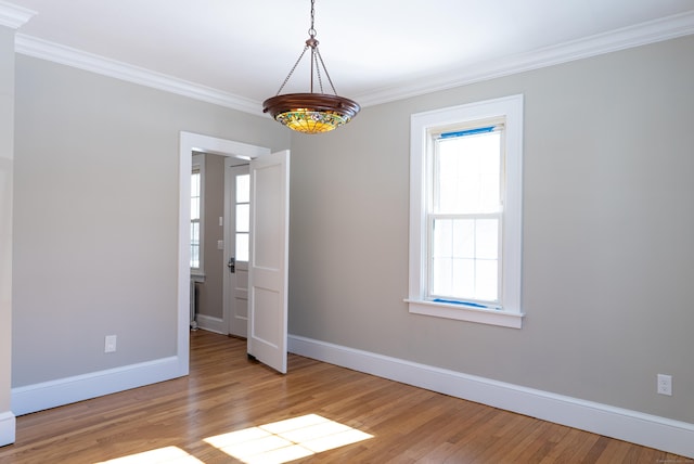 spare room with baseboards, ornamental molding, and wood finished floors