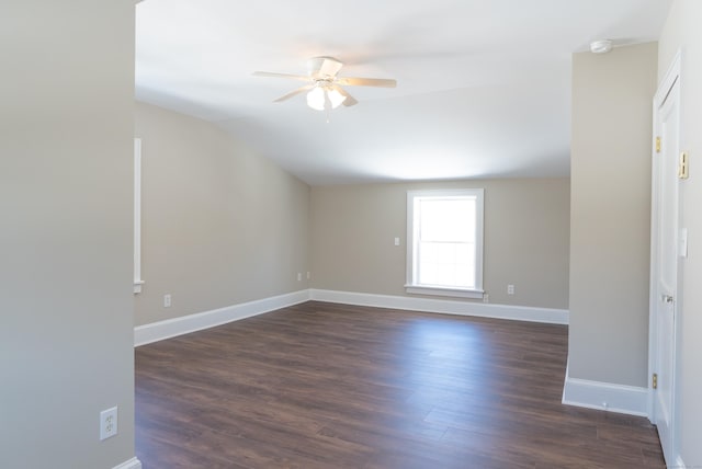 unfurnished room featuring dark wood-type flooring, vaulted ceiling, ceiling fan, and baseboards