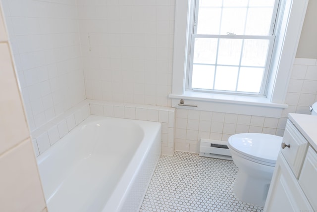 full bath featuring toilet, a bathing tub, baseboard heating, vanity, and tile walls