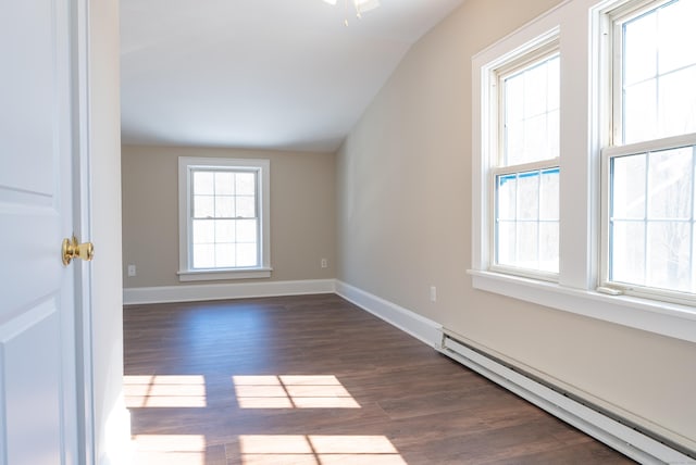 spare room featuring lofted ceiling, dark wood-type flooring, a baseboard radiator, and baseboards