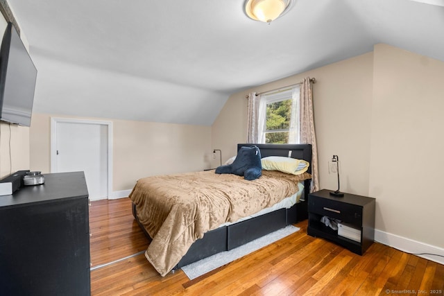 bedroom with hardwood / wood-style flooring, baseboards, and vaulted ceiling