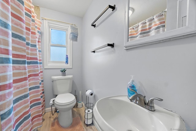 full bathroom with toilet, a shower with shower curtain, wood finished floors, a sink, and baseboards