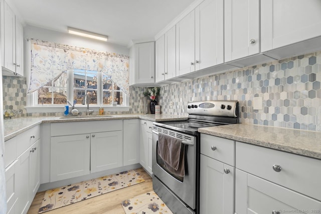 kitchen featuring a sink, light wood-style floors, white cabinets, stainless steel range with electric cooktop, and backsplash