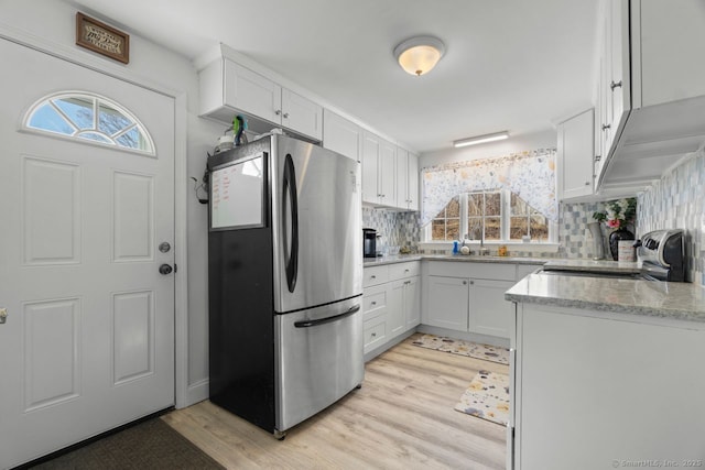 kitchen featuring freestanding refrigerator, white cabinetry, and light wood-style flooring