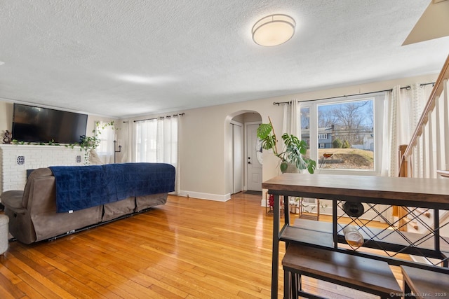 living area featuring arched walkways, light wood-type flooring, and a wealth of natural light