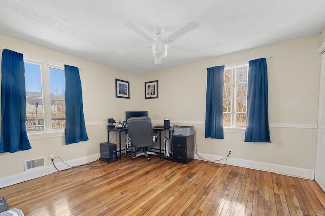 office featuring a ceiling fan, wood-type flooring, visible vents, and baseboards