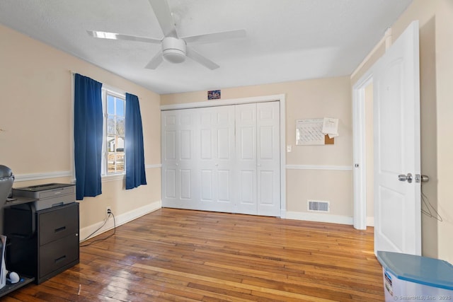 bedroom featuring hardwood / wood-style flooring, a closet, visible vents, and baseboards