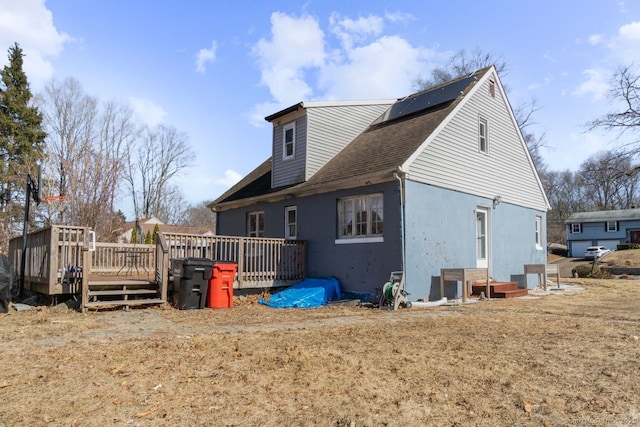 view of home's exterior with roof mounted solar panels and a deck