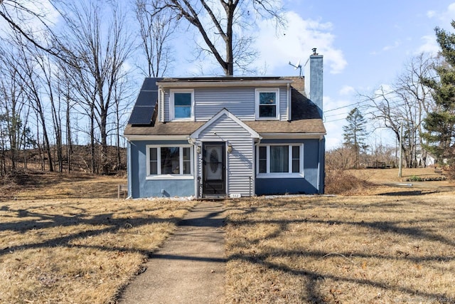 view of front facade featuring a shingled roof, a chimney, and stucco siding