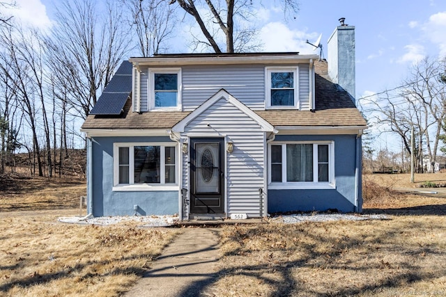 bungalow-style home with a shingled roof, a chimney, and stucco siding