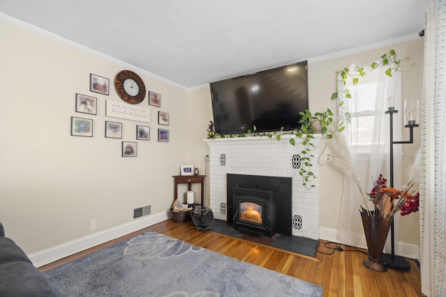 living area featuring crown molding, a fireplace, baseboards, and wood finished floors