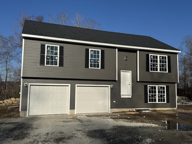 split foyer home with driveway, roof with shingles, and an attached garage