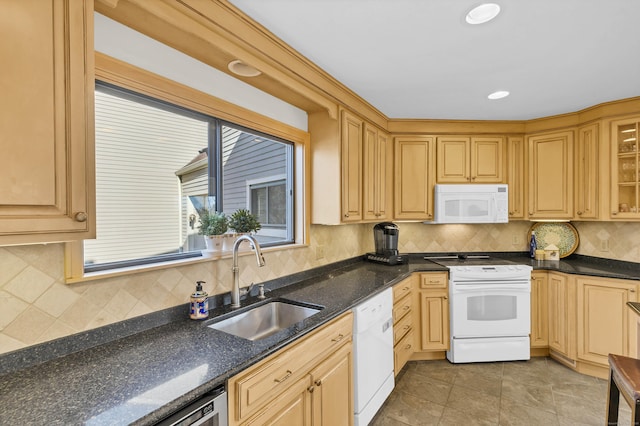 kitchen with light tile patterned floors, decorative backsplash, a sink, dark stone counters, and white appliances