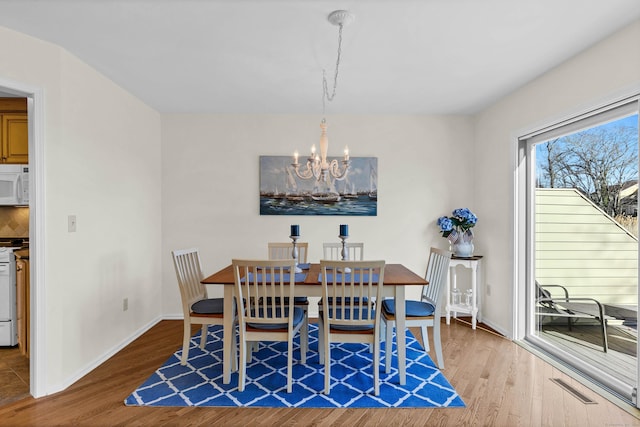 dining room with an inviting chandelier, visible vents, baseboards, and wood finished floors