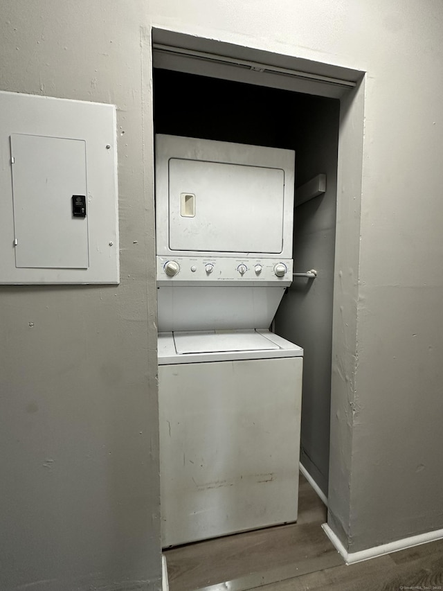 laundry room with laundry area, electric panel, dark wood finished floors, and stacked washer / drying machine