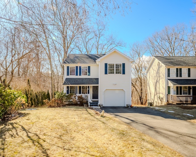 traditional-style home featuring an attached garage, driveway, a porch, and roof with shingles