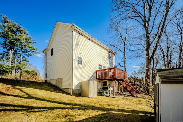 back of house with a deck, an outbuilding, a lawn, and stairway