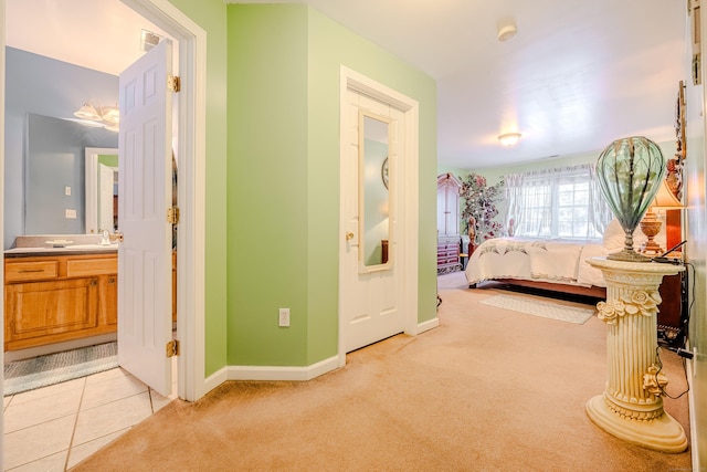 bedroom featuring visible vents, light carpet, a sink, light tile patterned flooring, and baseboards