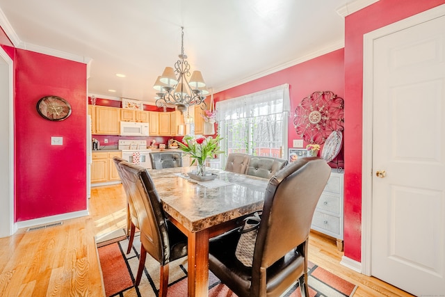 dining area featuring a notable chandelier, visible vents, baseboards, ornamental molding, and light wood-type flooring