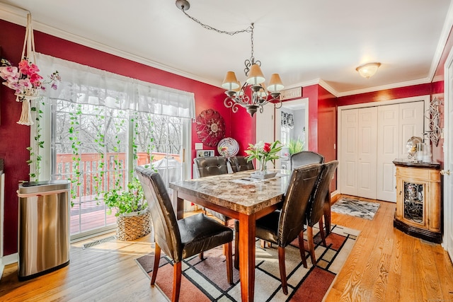 dining space with an inviting chandelier, light wood-type flooring, visible vents, and crown molding