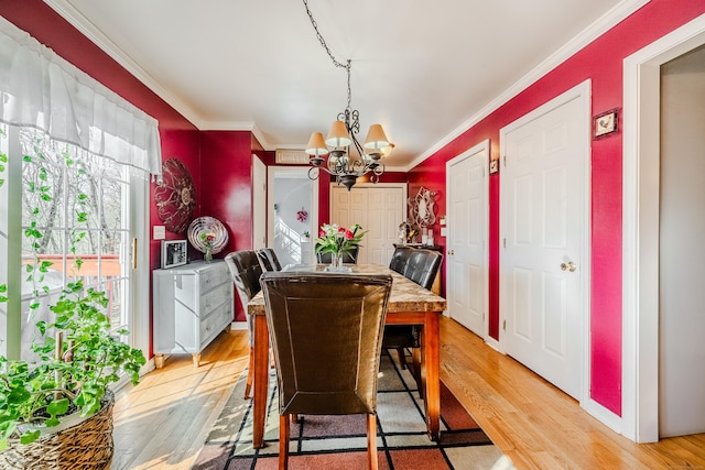 dining space with a chandelier, ornamental molding, and light wood finished floors