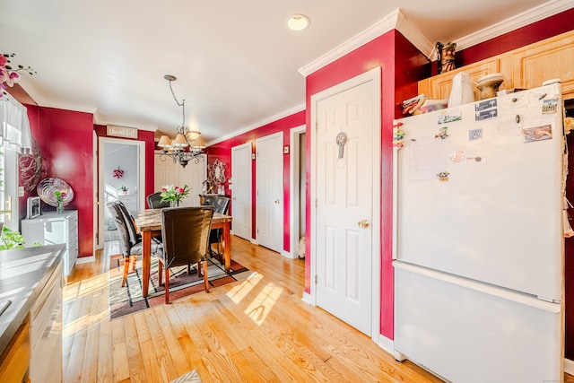 dining space with light wood-type flooring, crown molding, baseboards, and an inviting chandelier