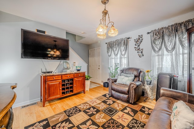 living area with a chandelier, light wood-style flooring, visible vents, and baseboards