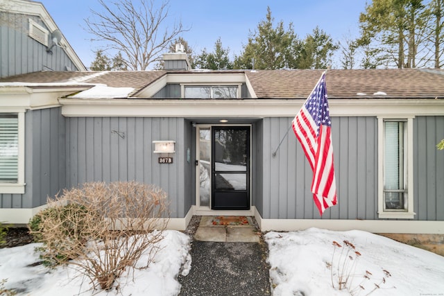 entrance to property with a shingled roof, a chimney, and board and batten siding