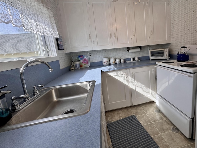 kitchen featuring a toaster, white electric stove, white cabinets, and a sink