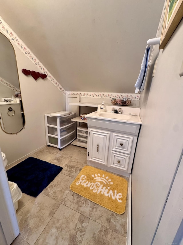 bathroom with lofted ceiling, baseboards, and vanity