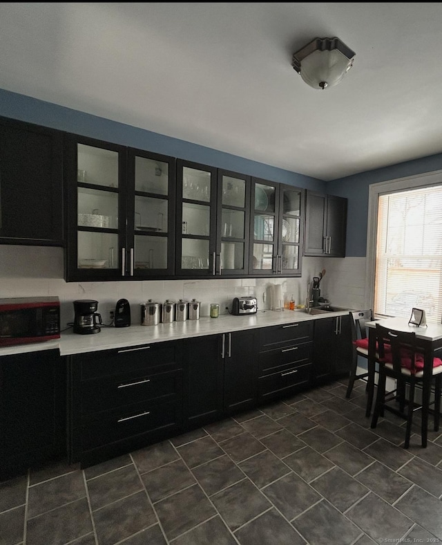 137 Fountain St Apt A7, New Haven, CT 06515 - kitchen featuring light countertops, decorative backsplash, glass insert cabinets, dark cabinets, and dark tile patterned flooring