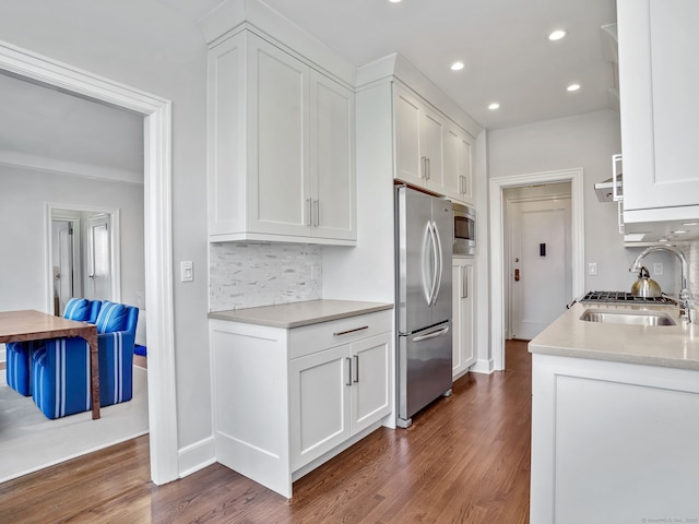 kitchen with dark wood-style floors, appliances with stainless steel finishes, a sink, and tasteful backsplash