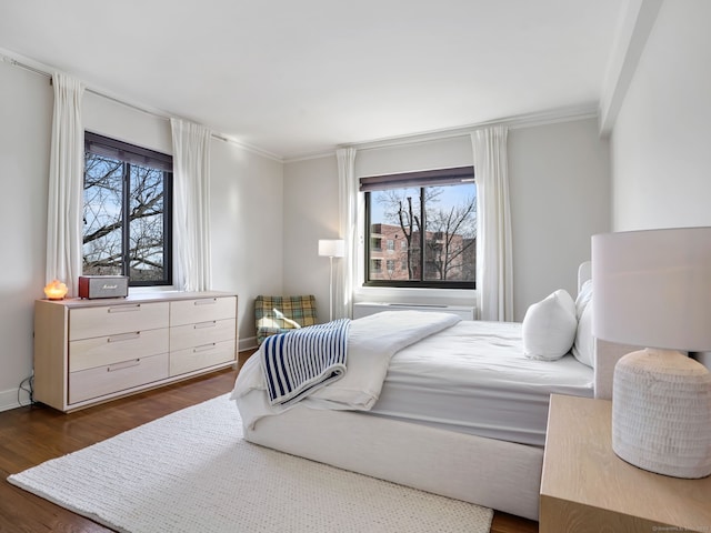 bedroom featuring baseboards, ornamental molding, and dark wood finished floors