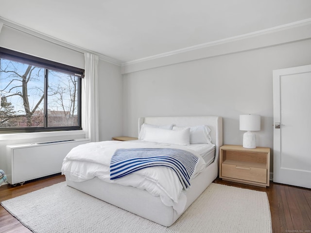 bedroom with radiator, wood finished floors, and crown molding