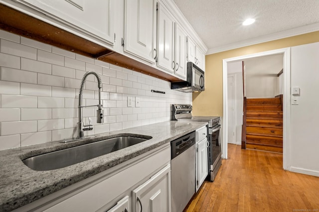 kitchen featuring stainless steel appliances, light wood-style floors, white cabinets, a textured ceiling, and a sink