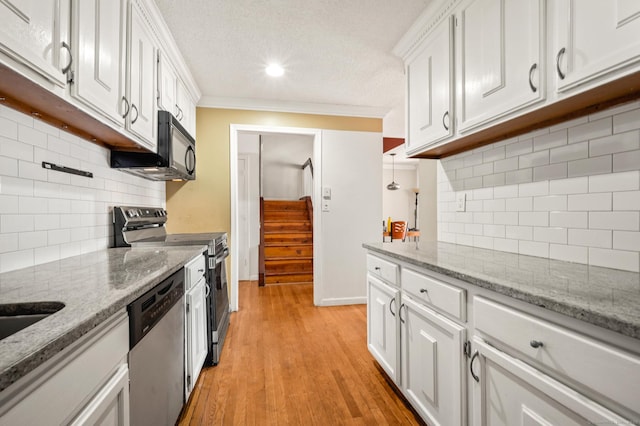 kitchen featuring ornamental molding, light wood-style flooring, a textured ceiling, stainless steel appliances, and white cabinets