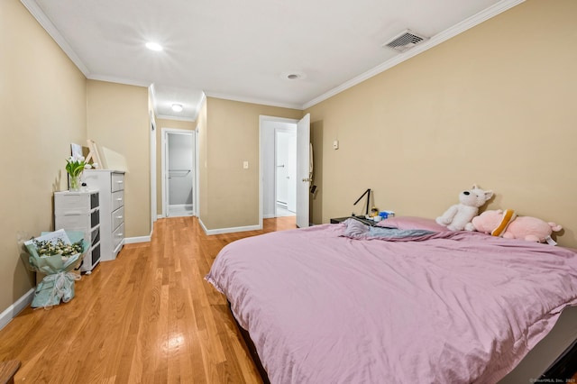 bedroom with ornamental molding, wood finished floors, visible vents, and baseboards